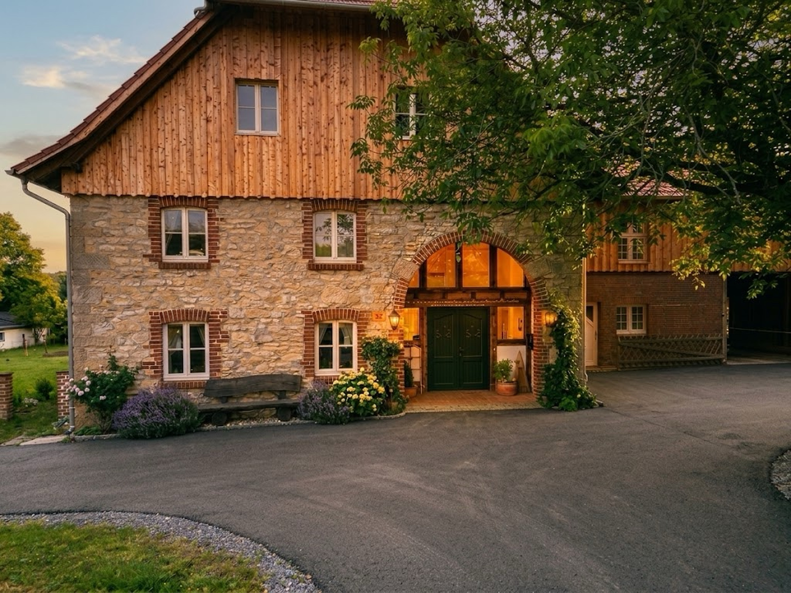 Naturstein- und Holzfassade eines ländlichen Wohnhauses in warmer Abendstimmung